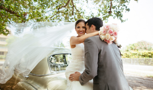 Newlywed couple standing by car