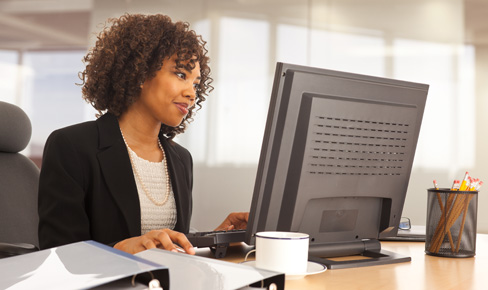 Woman sitting at desk, looking at computer screen
