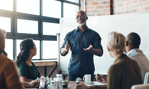 Man teaching to small group in front of white board.